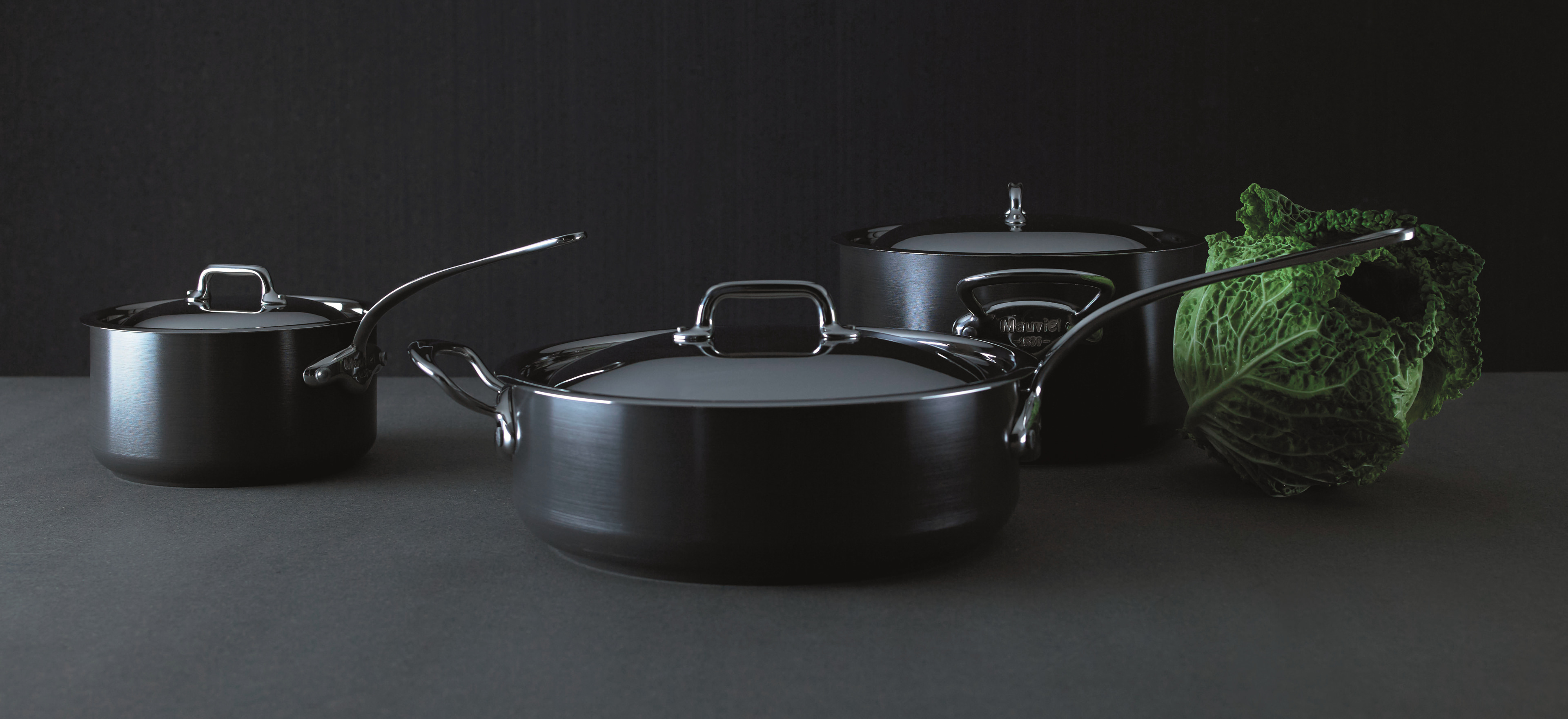 Various pans from across our cookware ranges arranged on a grey background.