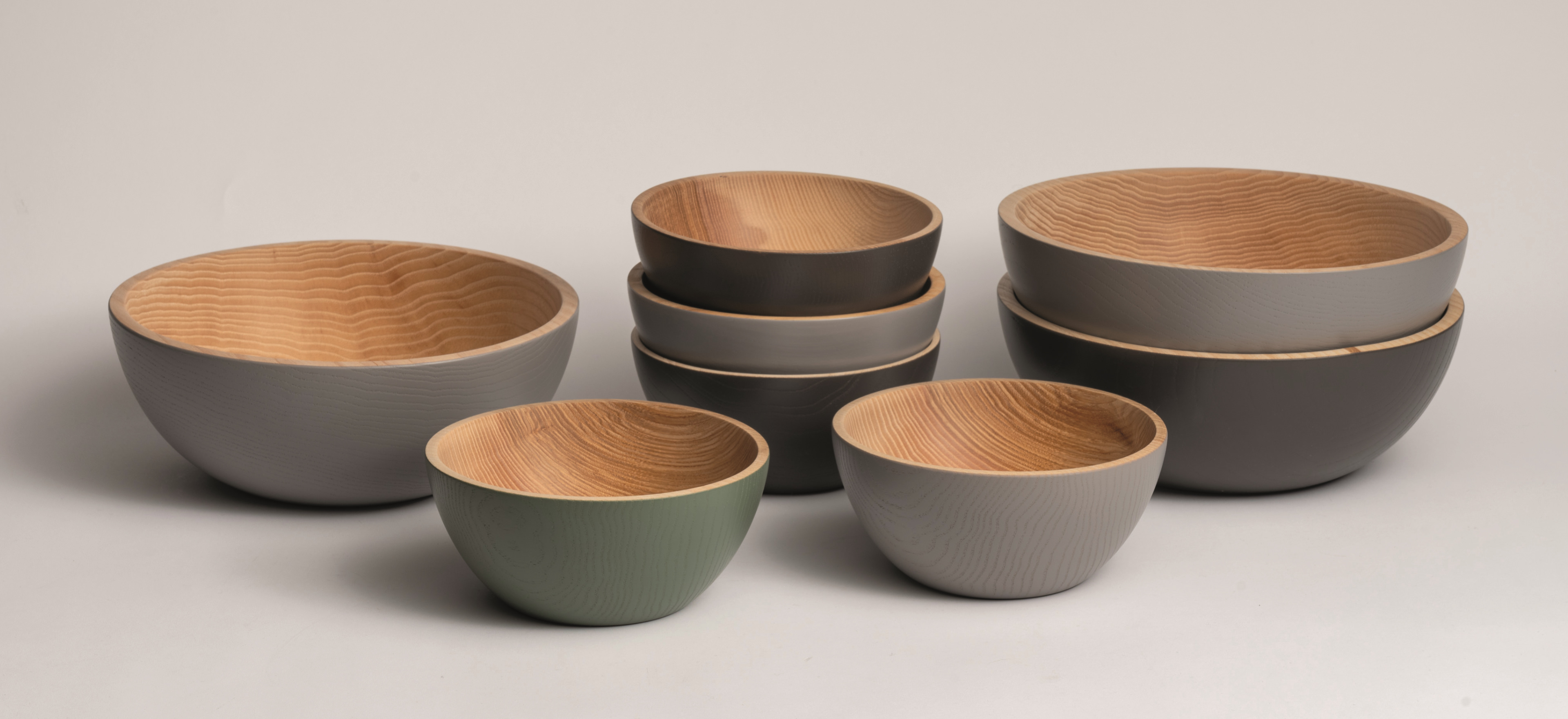 Maco coloured wooden bowls on a grey background.