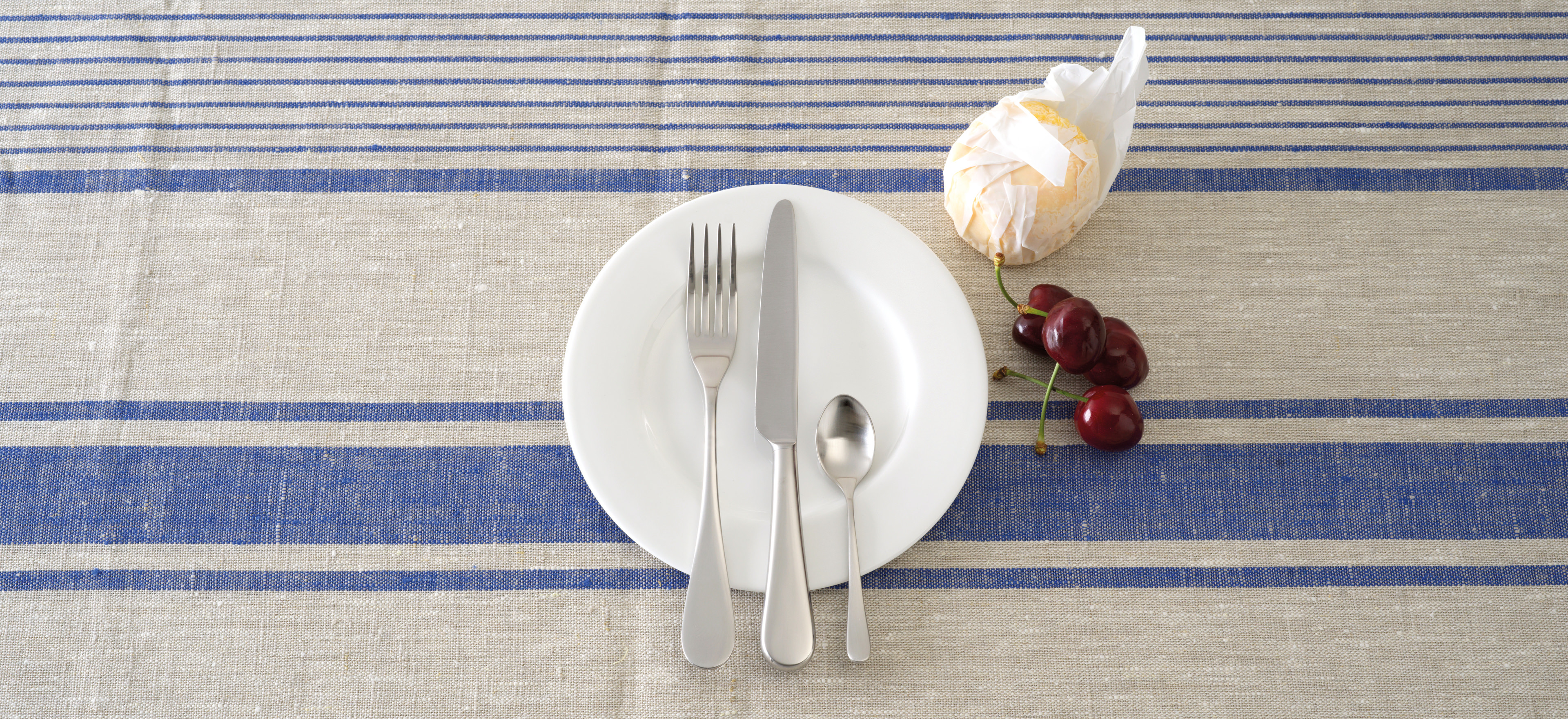 David Mellor English cutlery on a striped blue tablecloth background.
