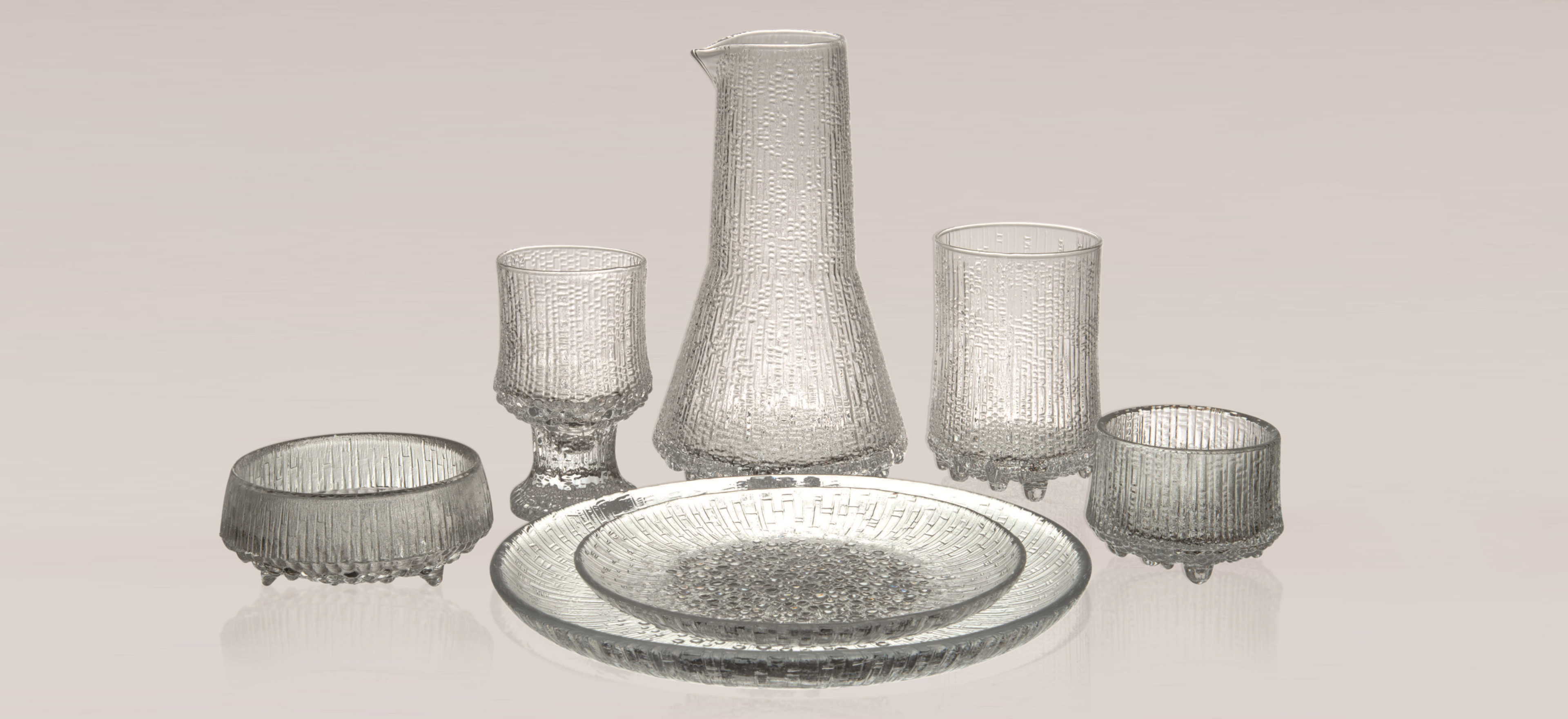 Iittala Ultima Thule glassware on grey background.