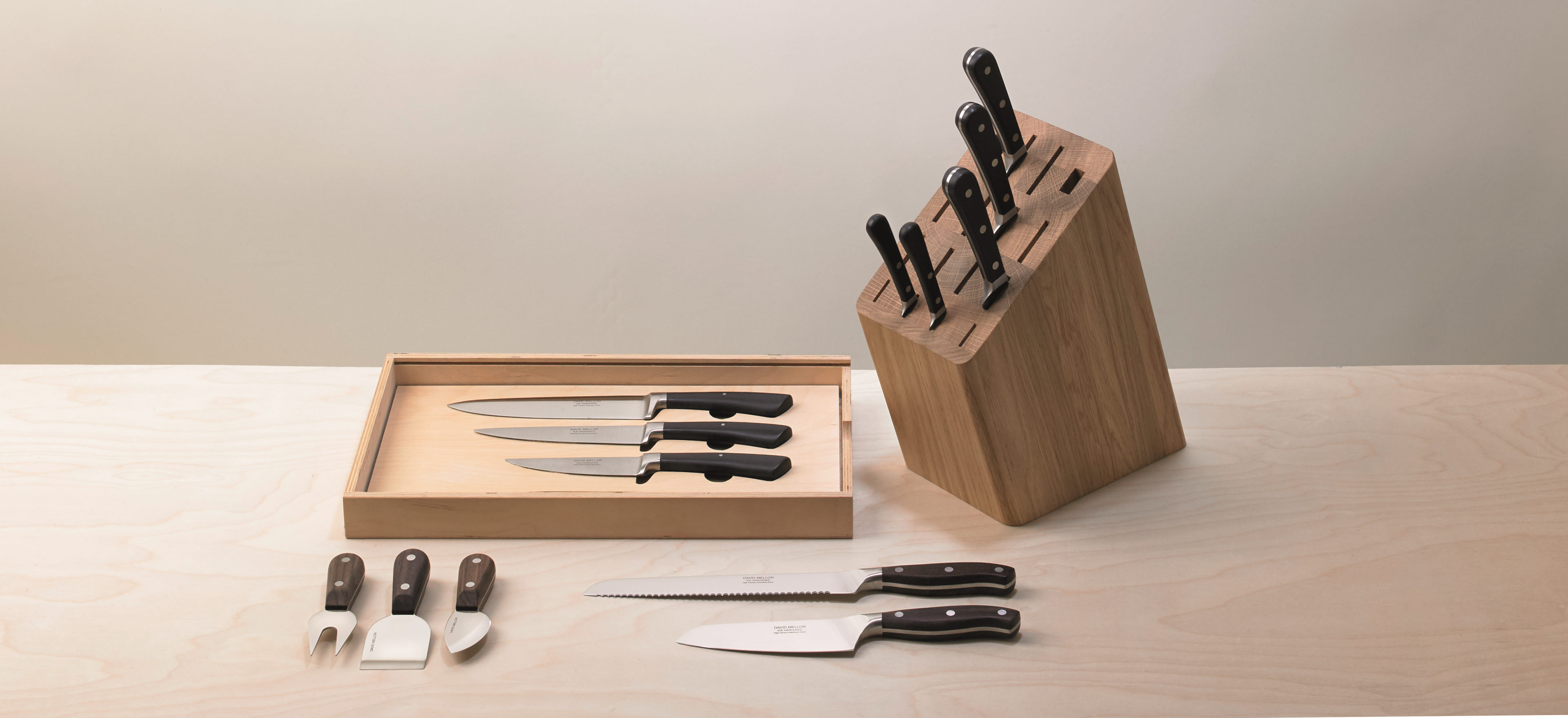 David Mellor kitchen knives and boards arranged on a cream background.