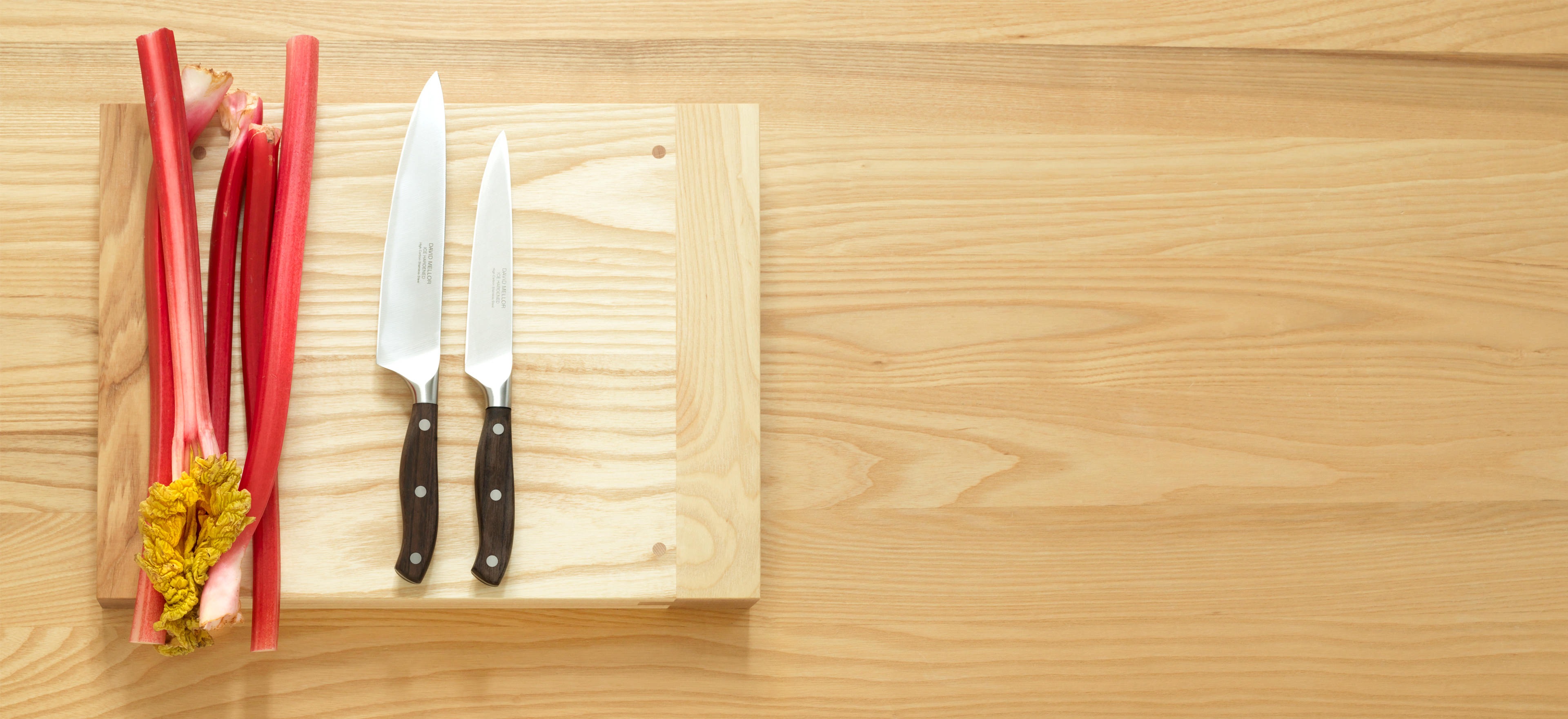 David Mellor rosewood kitchen knives on a David Mellor chopping board with rhubarb.