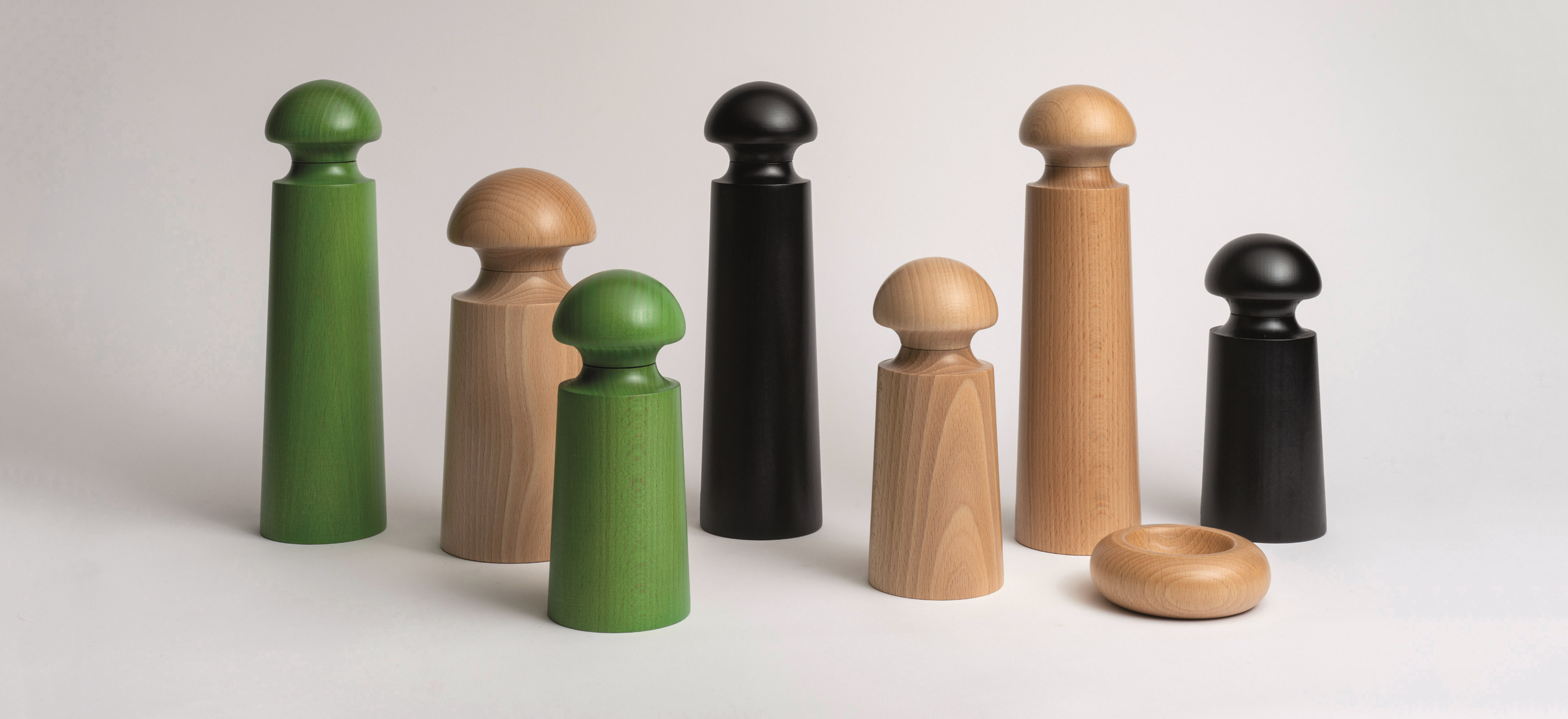 Various David Mellor pepper grinders and pinch pots on a grey background.