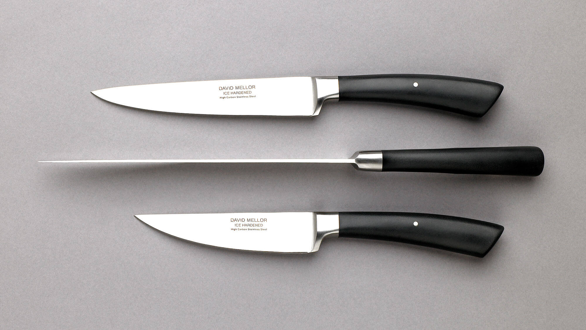 Black handle knives on a grey background.