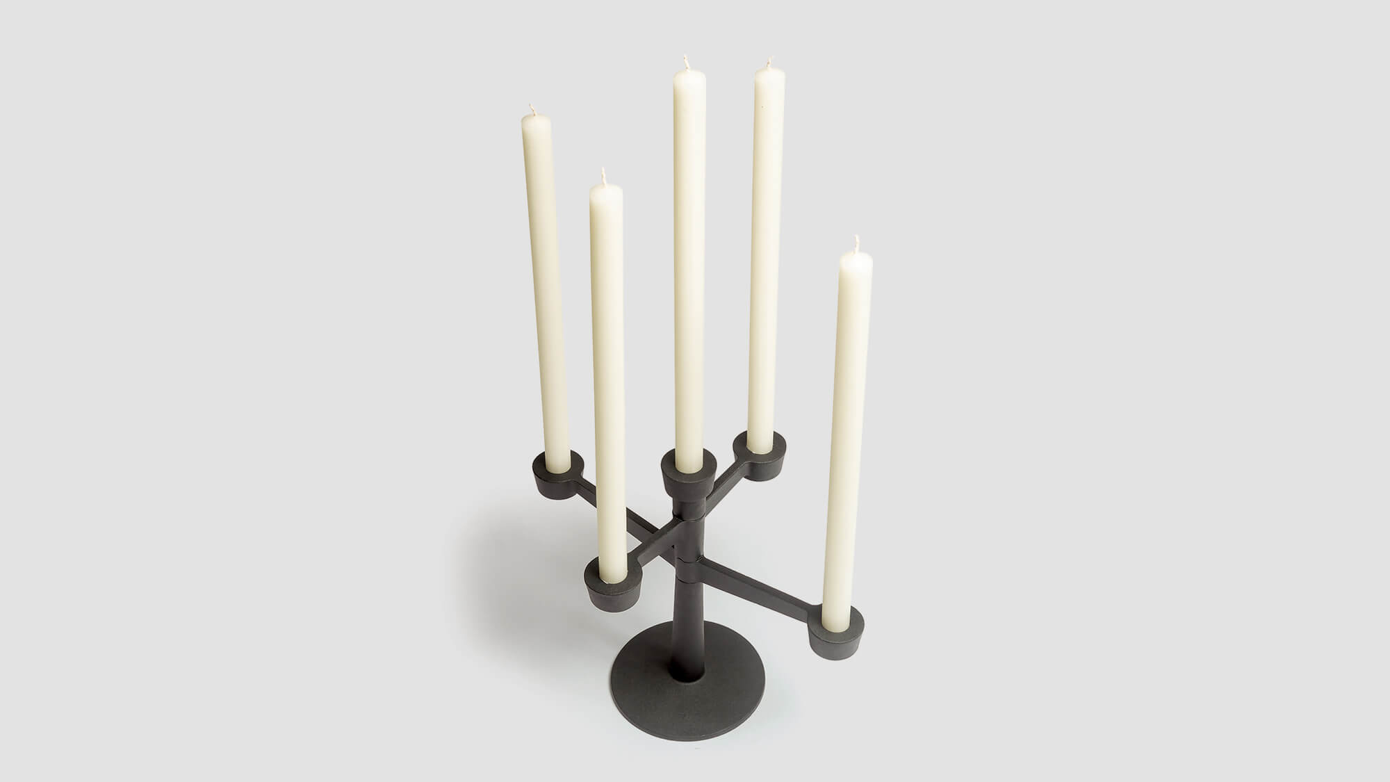 Cast iron candelabrum displayed with church candles on a grey background.