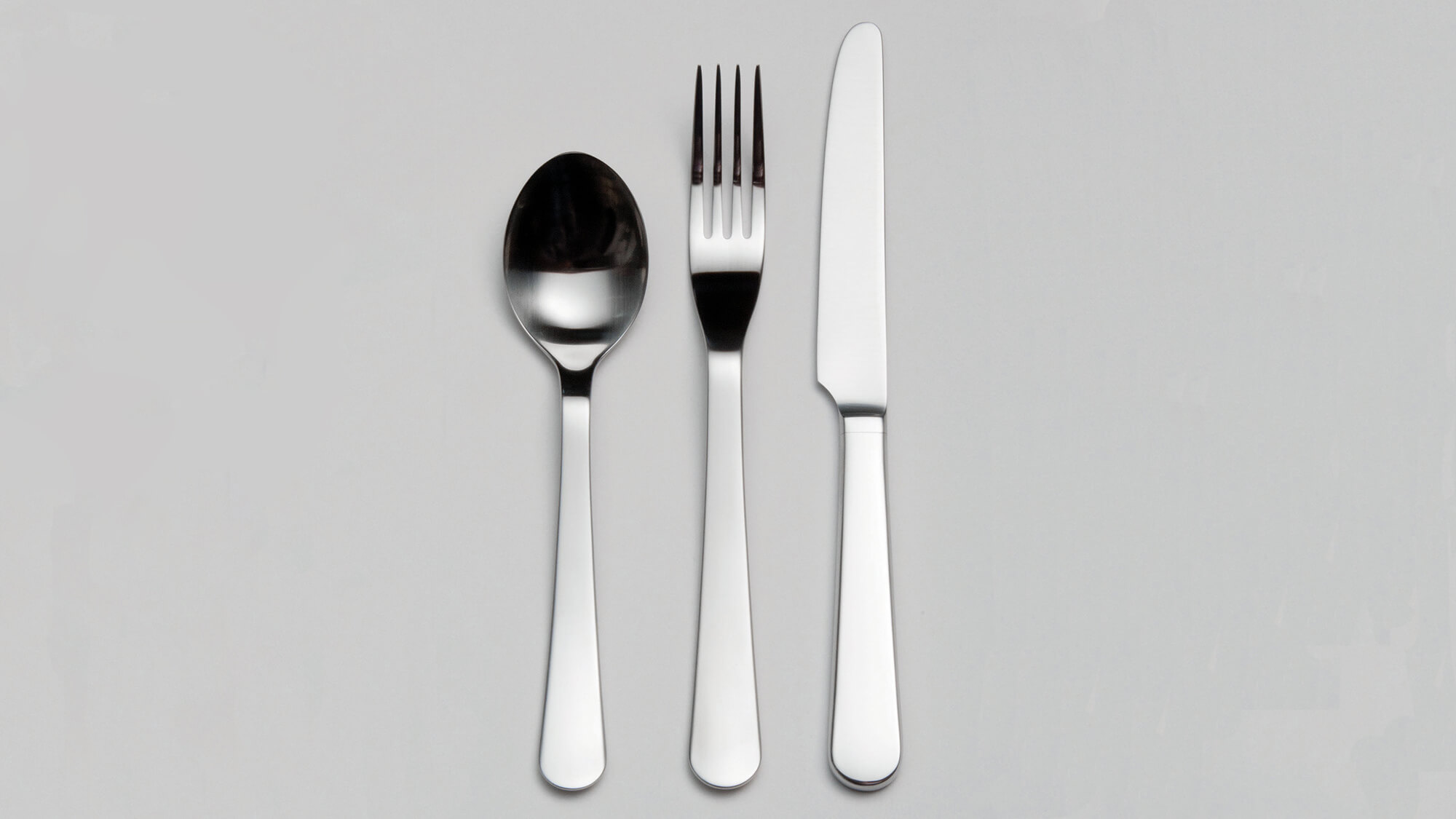 Chelsea stainless steel cutlery items displayed in a line on a grey background.