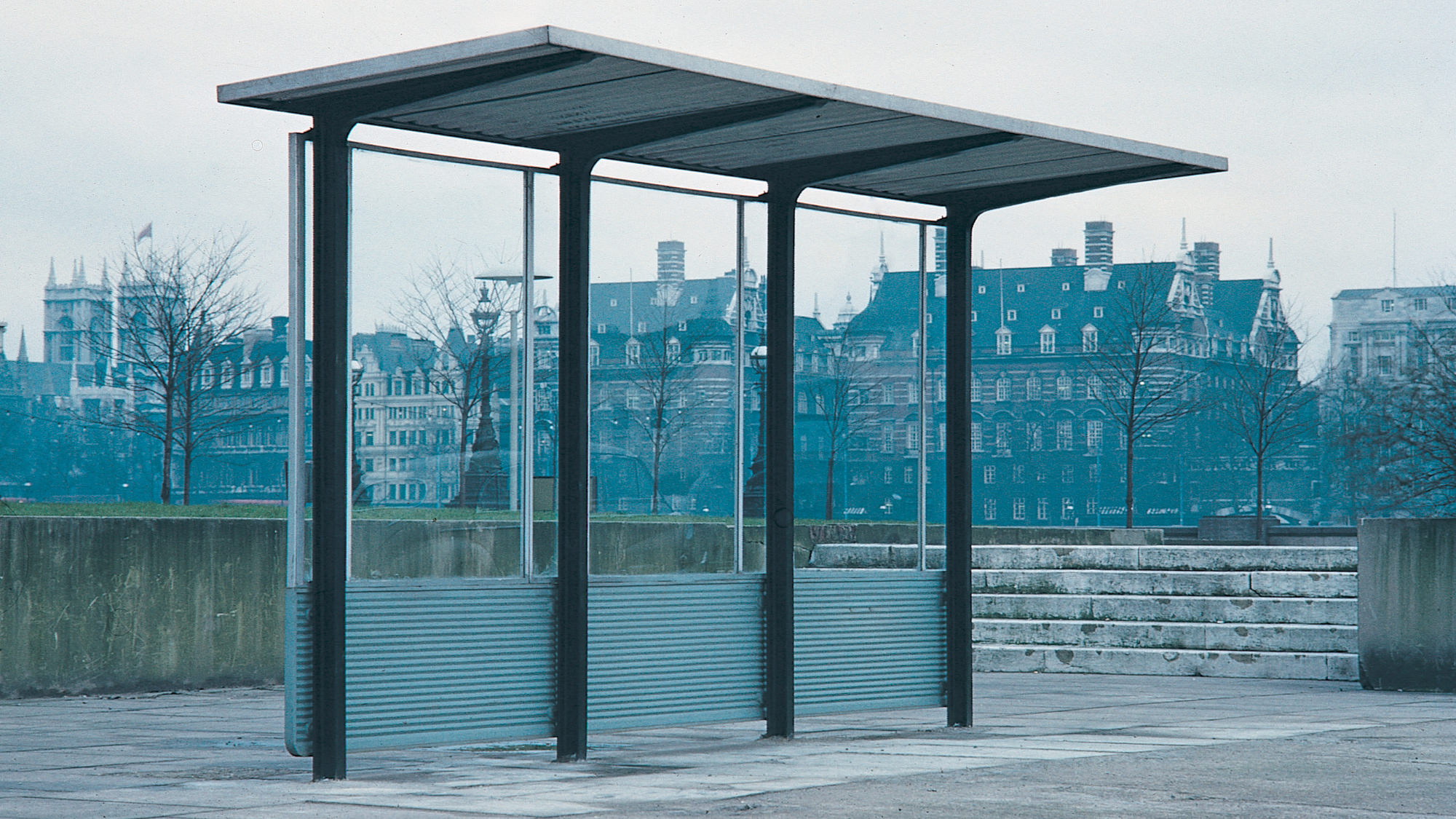 Bus shelter in galvanised steel shown in situ in an unknown street.