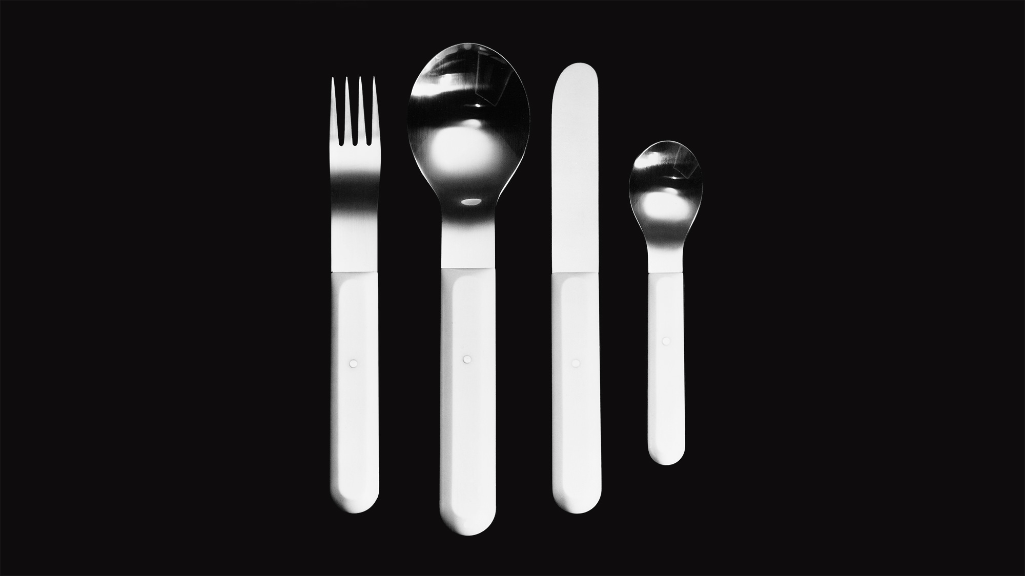 Chinese ivory cutlery in a line on a black background.