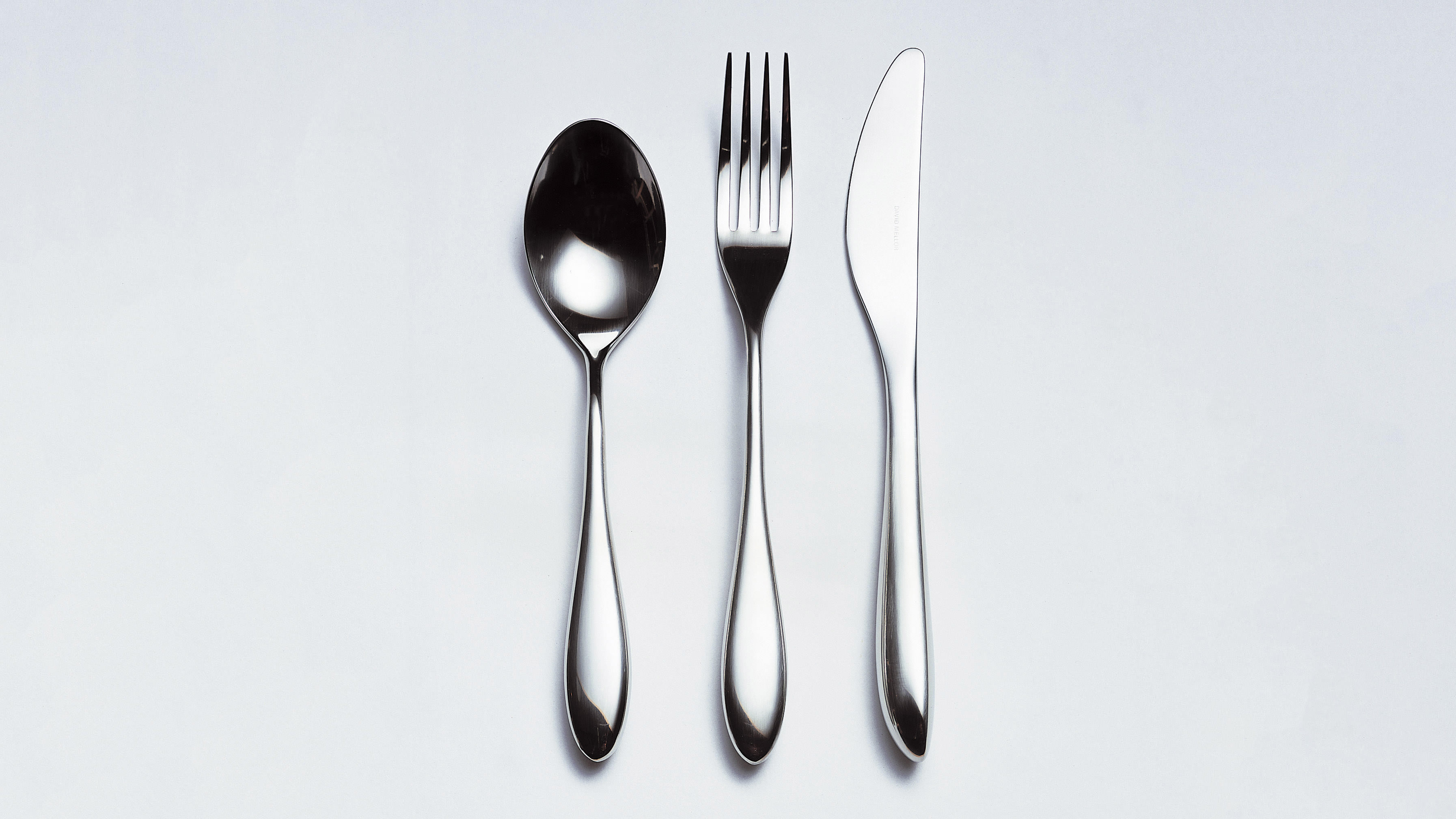 City stainless steel cutlery items displayed in a line on a grey background.