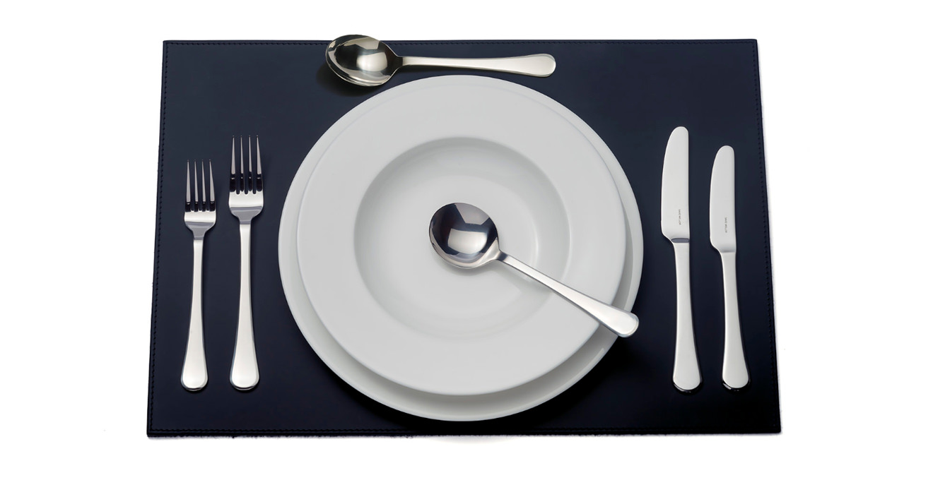 Classic cutlery laid out on a table mat.