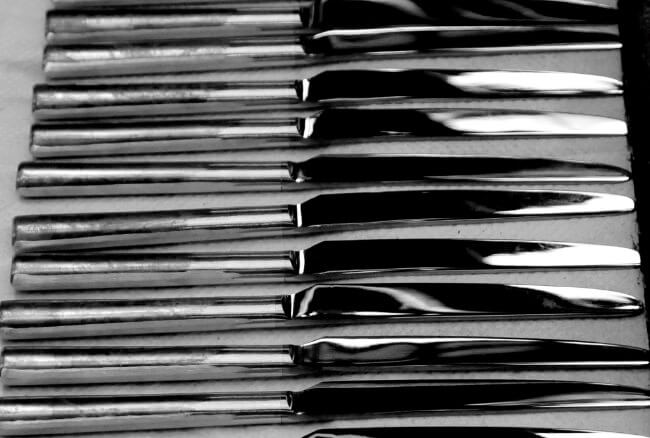 Table knives lined up within a finishing tray.