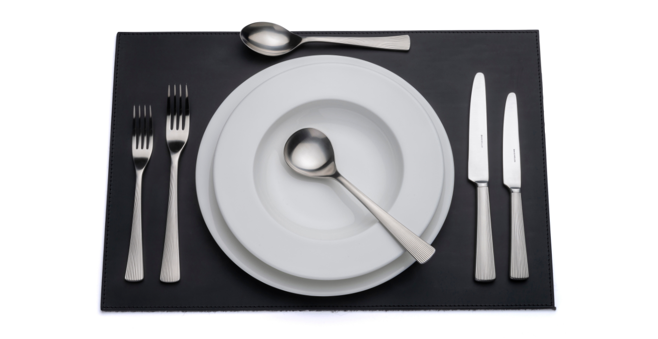 Liner cutlery laid out on a table mat.